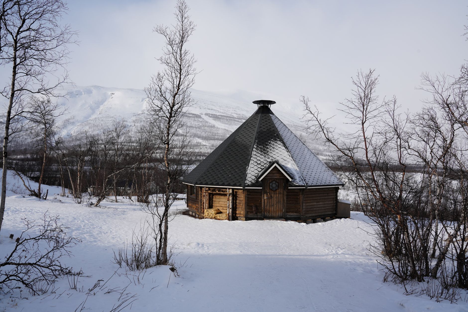 Wooden two person outdoor sauna cabin on a deck with snow around it