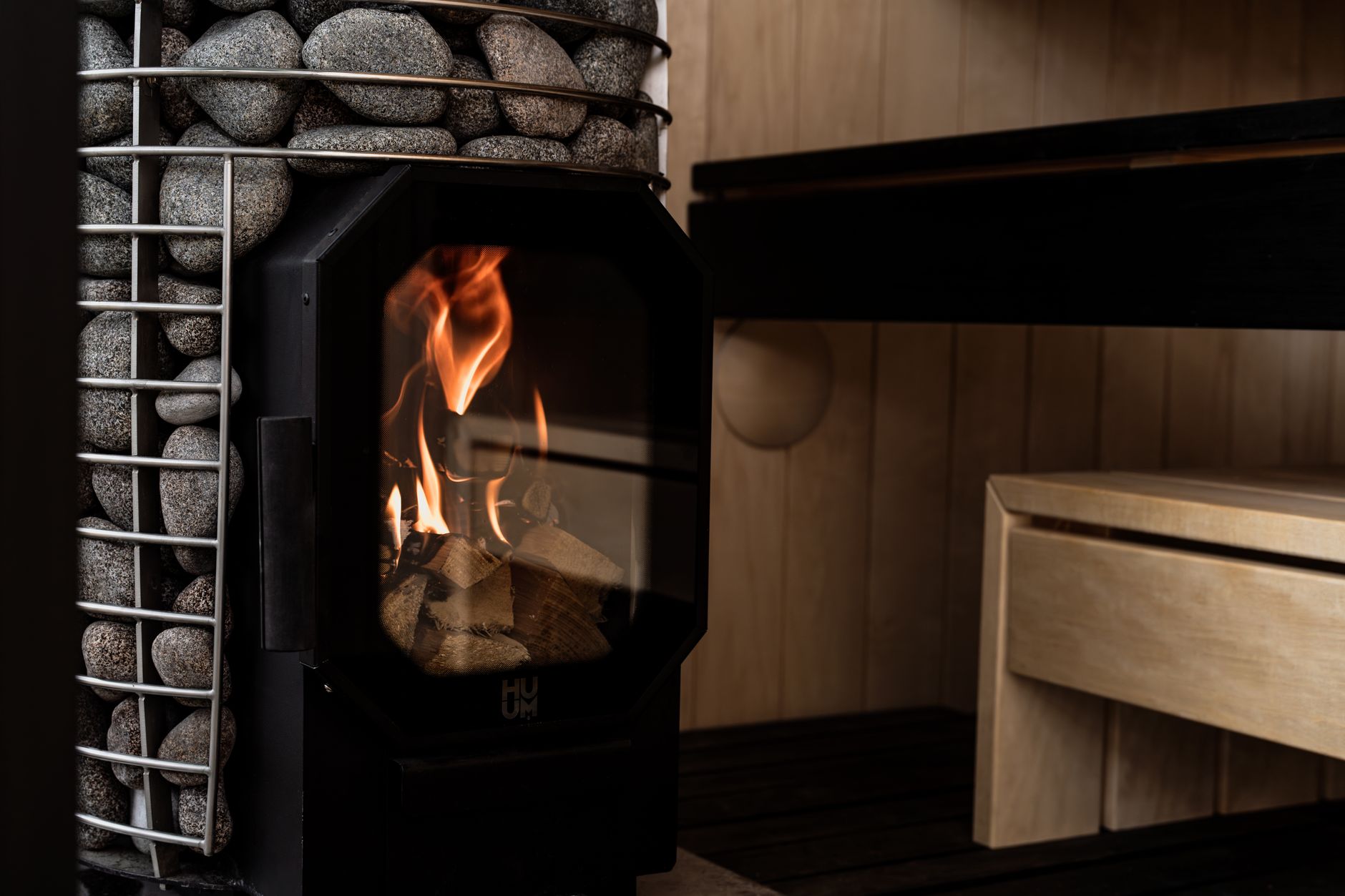 Wood burning sauna stove with pile of hot stones inside sauna